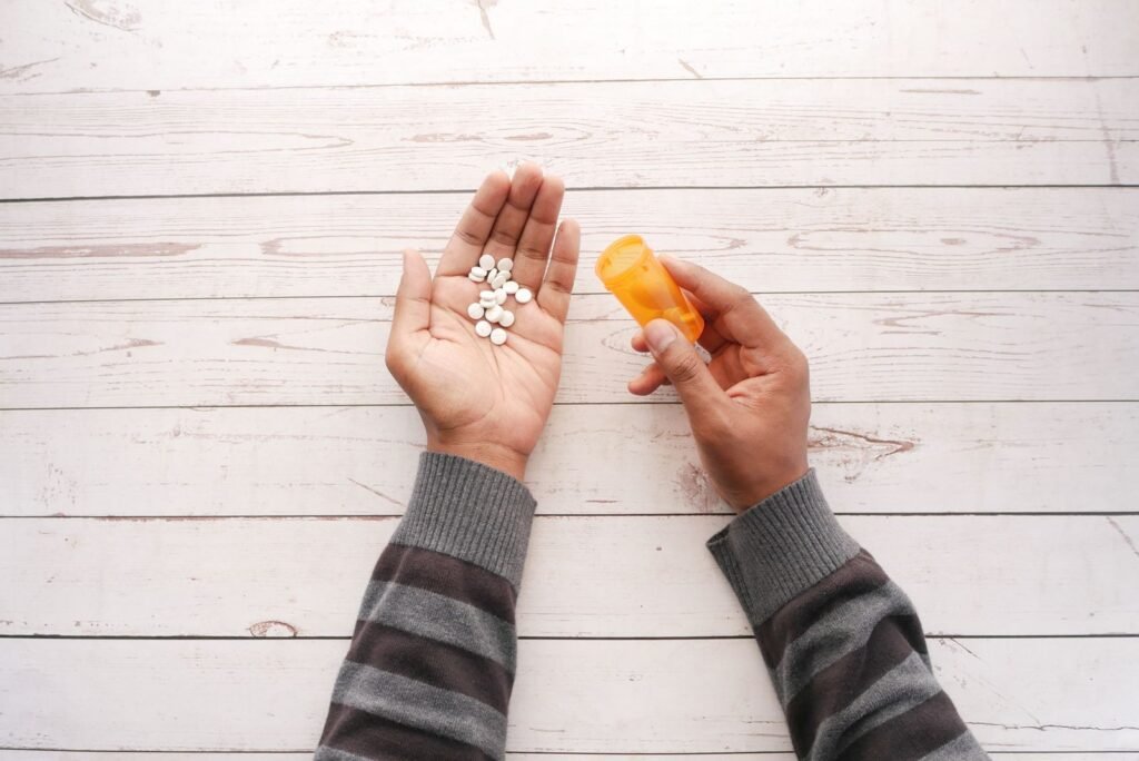 Hands holding buprenorphine tablets next to a prescription bottle
