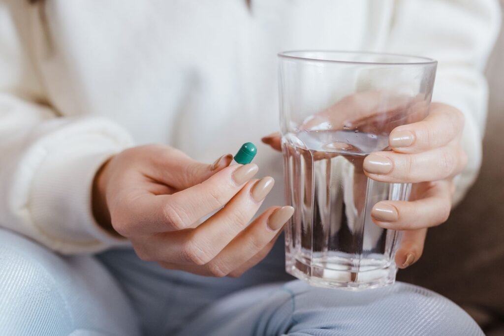 Adult hands holding a pill and a glass of water before taking a morning medication