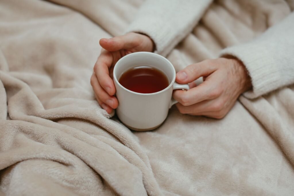 A person wrapped in a blanket holding a warm cup of tea