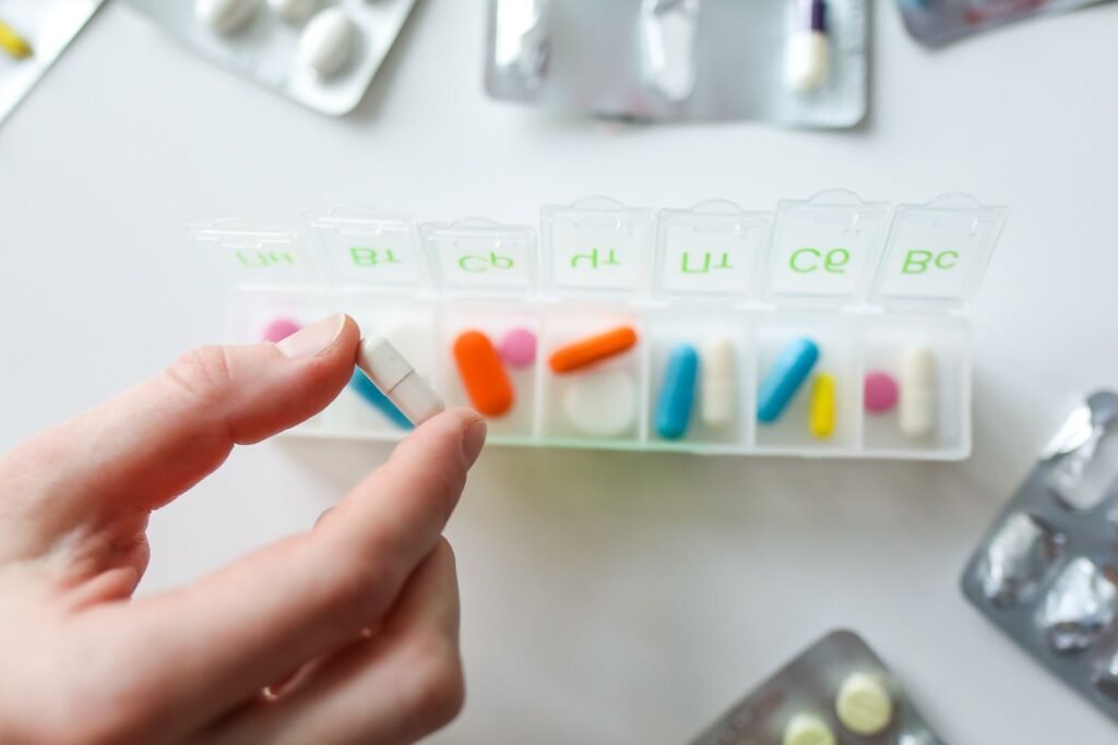 A hand selecting a pill from a weekly pill organizer