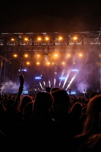 Silhouettes of a crowd at a concert facing brightly lit stage lights